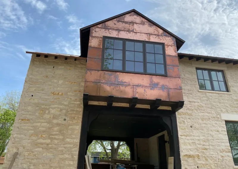 Copper metal panel facade on a stone building for Roof Repair in Timberlake