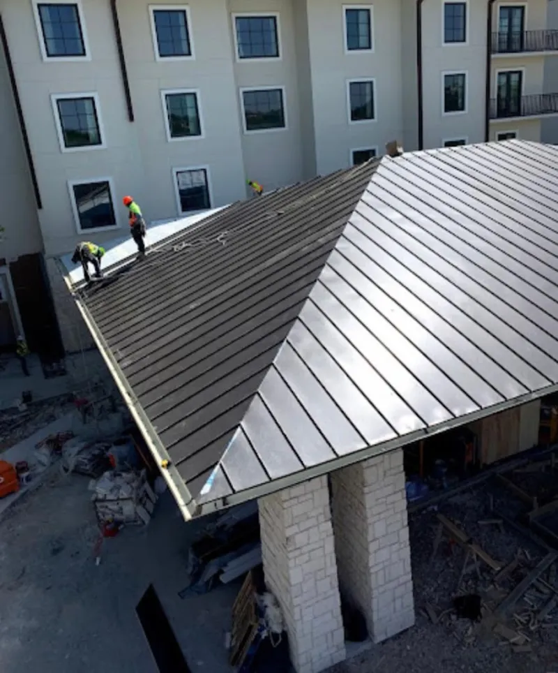 Crew installing standing seam metal roof panels on a commercial project in Timberlake